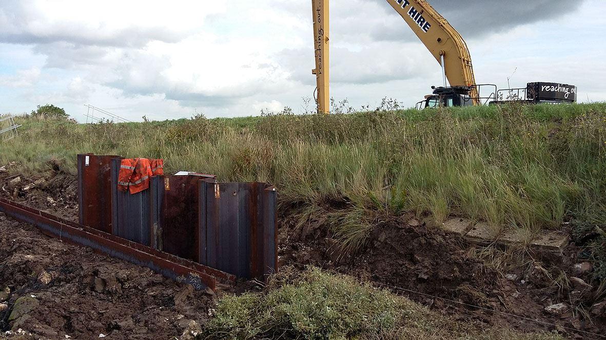 Excavator working behind a bank with no visual of the work being undertaken