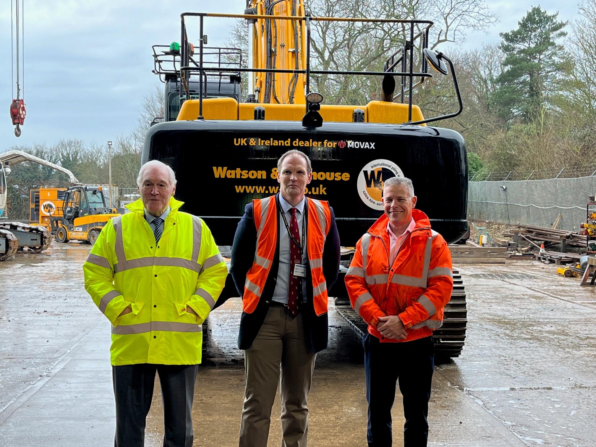 Mr Robin Watson (CEO and Founder), MP Daniel Poulter and Phillip Bell (Managing Director) standing in front of an excavator