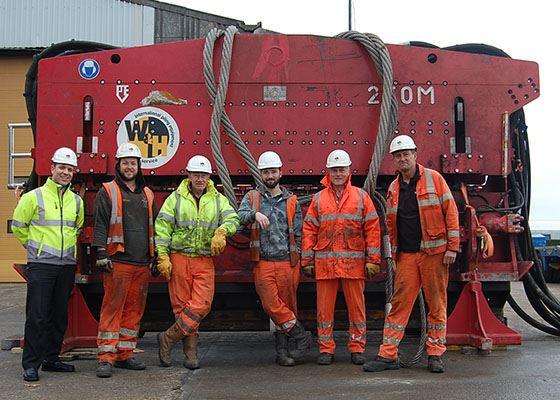 Dieseko PVE 250M vibratory hammer with 6 men standing in front with hi vis and helmets