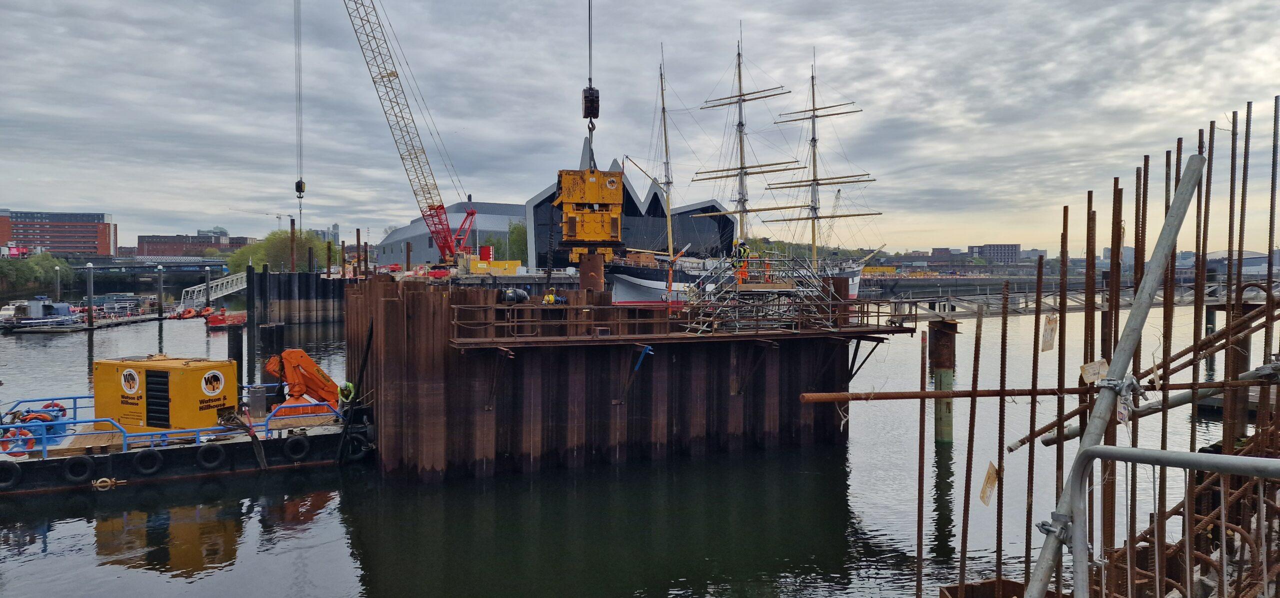 Image showing Watson & Hillhouse crane suspended vibrator and power pack installing tube and sheet piles to create a cofferdam and pier for the new Govan Partick Bridge over the River Clyde